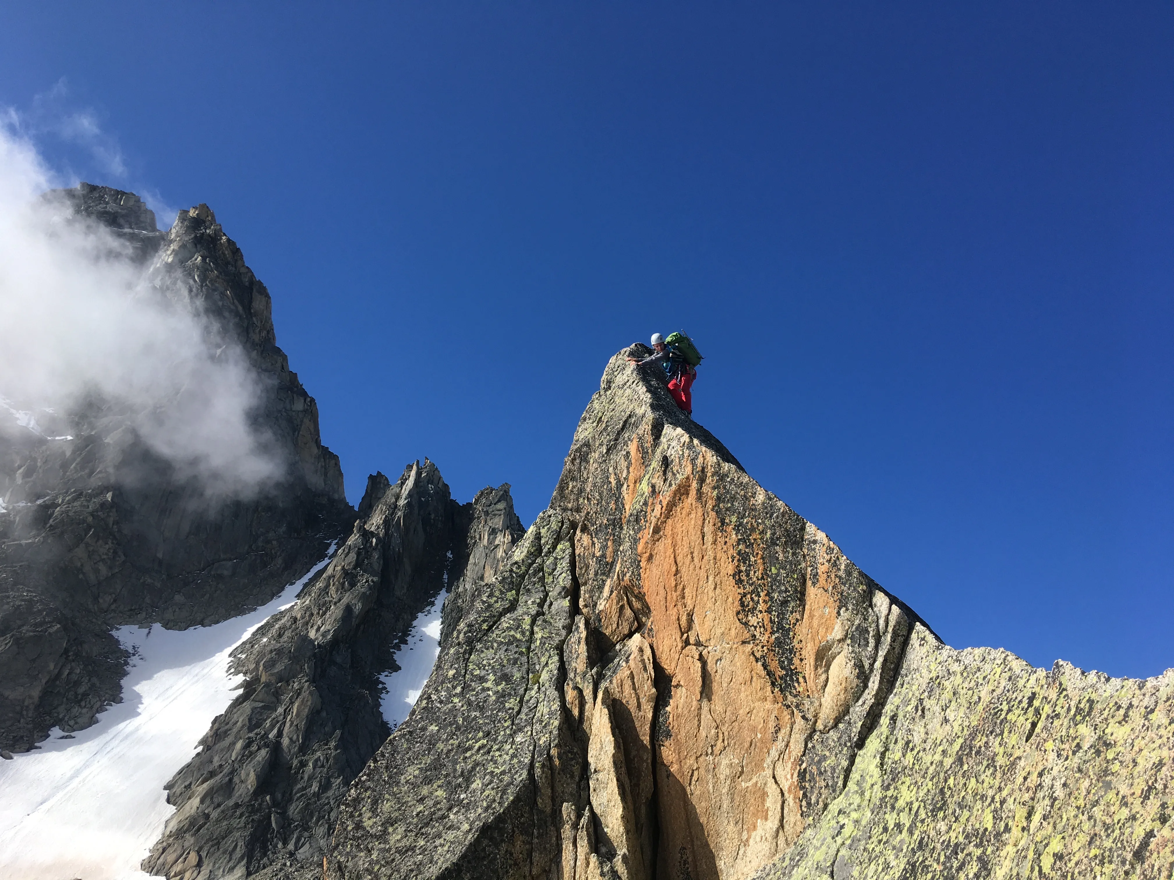 Alpiniste sur une arête rocheuse en haute montagne